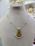 Gold and white pearl necklace displayed on a beige fabric jewelry bust, featuring a decorative gold pendant with hanging pearls.